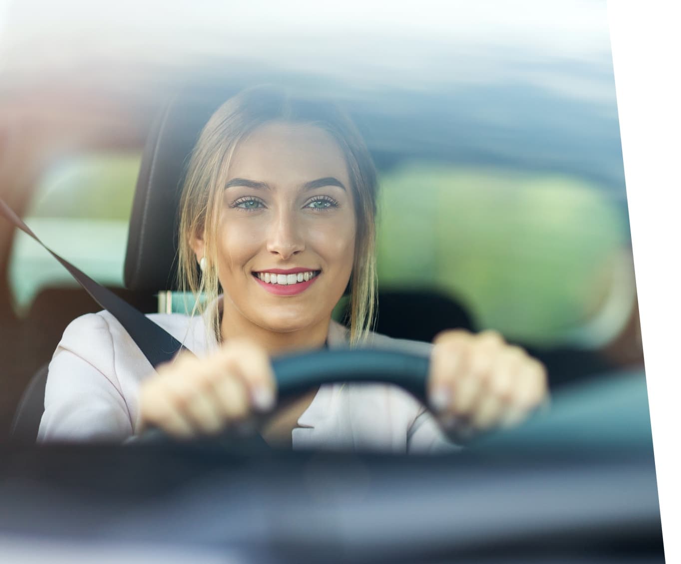 A woman smiling driving a car