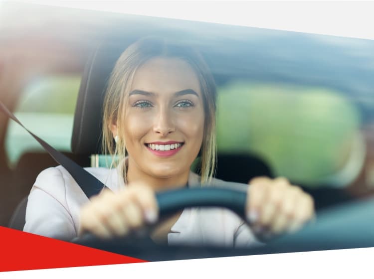 A woman smiling driving a car